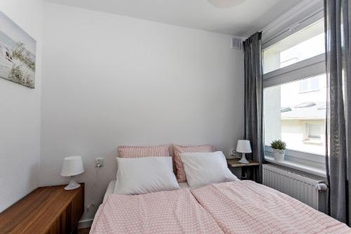 sypialnia z łóżkiem z różowym kocem i oknem w obiekcie Promenada moj-sopot pl w mieście Sopot