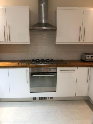 a kitchen with white cabinets and a stove top oven at Home from Home at Number 2 in Edinburgh