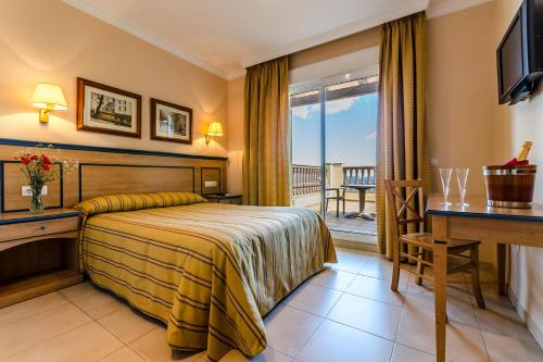 a hotel room with a bed and a desk and a balcony at Hotel Mirador in Algeciras