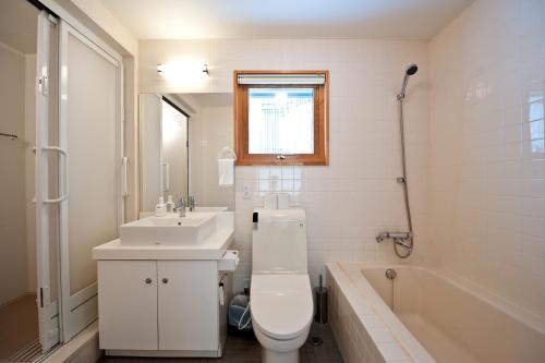 a bathroom with a toilet and a sink and a tub at Avalon in Kutchan