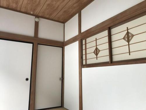 a room with white walls and wooden ceilings and doors at Guest House Itokawa in Matsuzaki