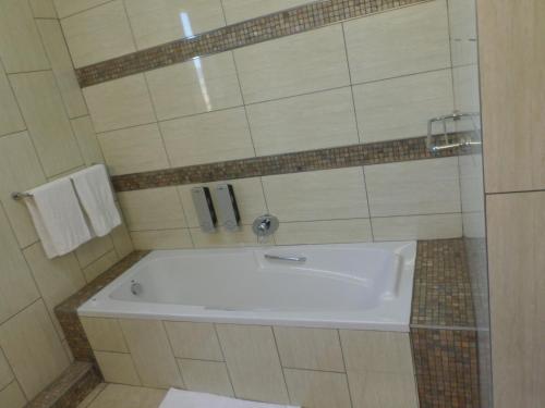 a bath tub in a bathroom with a sink at The Links Guest House in Pretoria