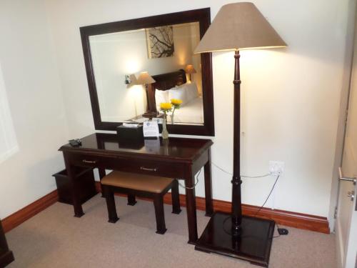 a desk with a lamp and a mirror in a room at The Links Guest House in Pretoria