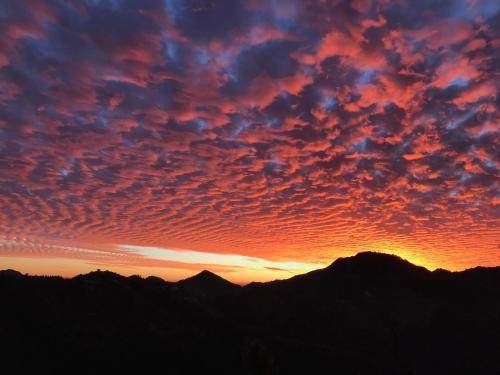 a sunset with mountains in the background at NamaStay Himalayas, KANATAL in Kanatal