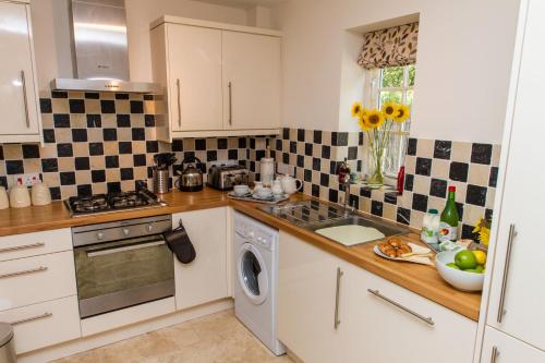 a kitchen with white cabinets and a sink and a dishwasher at Broads Reach in Stalham