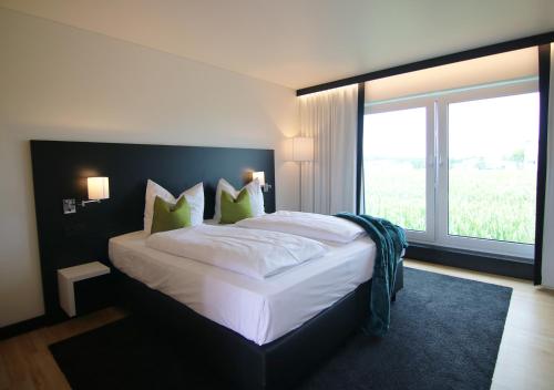 una camera da letto con un grande letto con una grande finestra di BG Hotel by WMM Hotels a Bad Grönenbach