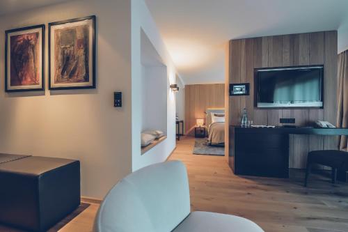 a hotel room with a television and a living room at Elizabeth Arthotel Adults Only in Ischgl