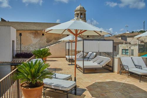 a group of chairs and an umbrella on a patio at Cas Comte Suites & Spa - Adults Only in Lloseta