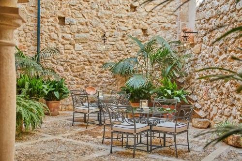 a patio with a table and chairs and a stone wall at Cas Comte Suites & Spa - Adults Only in Lloseta