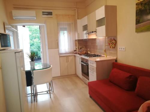 セゲドにあるRókusi Apartman Szegedの小さなキッチン(赤いソファ、赤い椅子付)