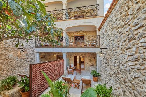 a stone building with a balcony and tables and chairs at Cas Comte Suites & Spa - Adults Only in Lloseta