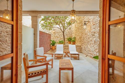 a patio with chairs and a table and a stone wall at Cas Comte Suites & Spa - Adults Only in Lloseta