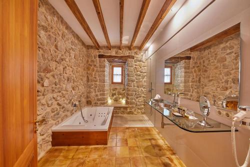 a bathroom with a tub and a stone wall at Cas Comte Suites & Spa - Adults Only in Lloseta