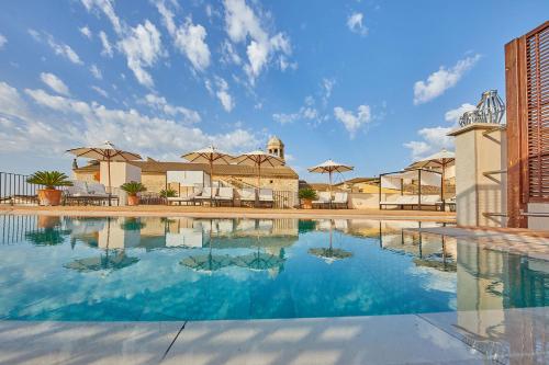 ein großer Pool mit blauem Wasser und Sonnenschirmen in der Unterkunft Cas Comte Suites & Spa - Adults Only in Lloseta