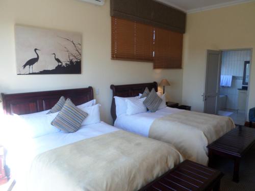 a hotel room with two beds and a painting on the wall at The Links Guest House in Pretoria