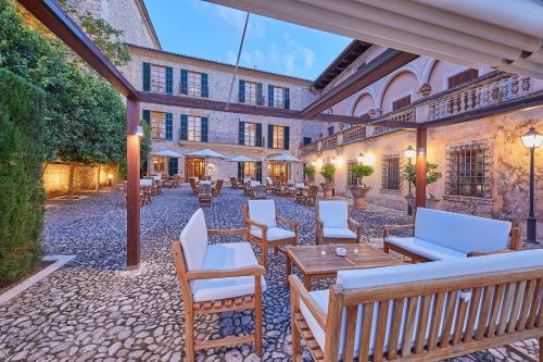 an outdoor patio with white chairs and tables at Cas Comte Suites & Spa - Adults Only in Lloseta