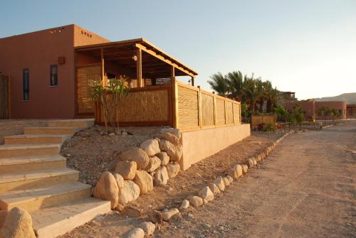 a house with a retaining wall and some rocks at Zman Arava in Zuqim