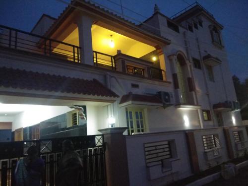 a large white house with people walking in front of it at Coimbatore Home Stay & Serviced Apartment in Coimbatore