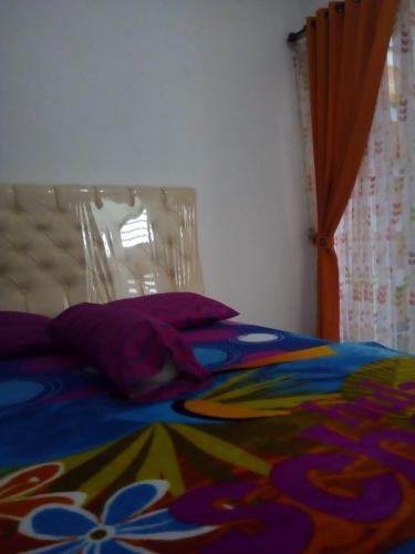 a bed with a colorful blanket and pillows on it at Vila Monex in Batu