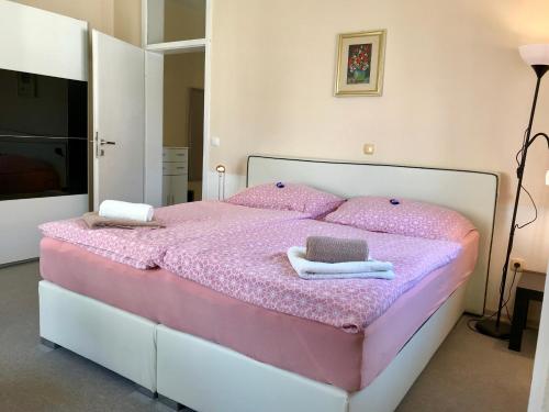 a bedroom with a pink bed with towels on it at Apartments Terme Ptuj in Ptuj