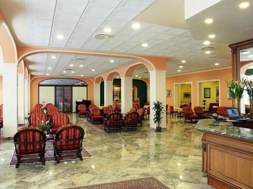 a lobby with red chairs and a waiting area at Hotel Columbia Terme in Abano Terme