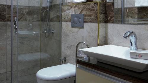 y baño con aseo, lavabo y ducha. en Elazig Gunay Hotel en Elazığ