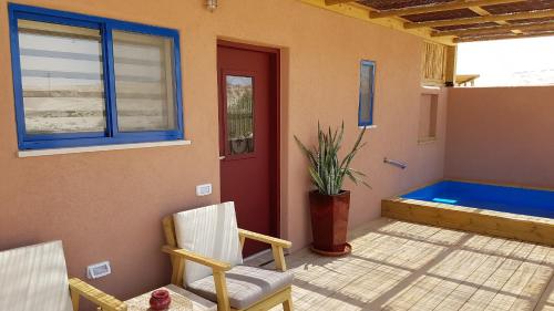 a porch with two chairs and a red door at Zman Arava in Zuqim