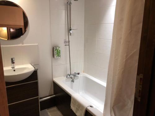 
a white bath tub sitting under a window in a bathroom at The Gulliver's Hotel in Warrington
