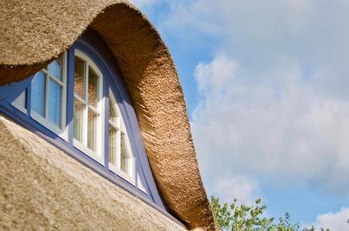 a window in the side of a thatched building at Haus Meerblau in Born