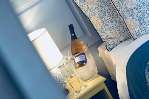 a bottle of wine on a table next to a bed at Guy's Thatched Hamlet in Barton