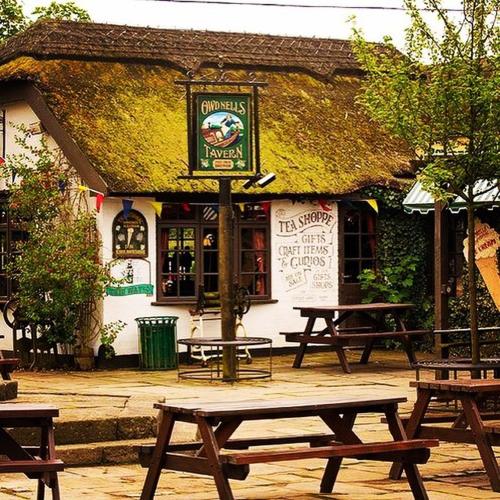 a group of picnic tables in front of a building at Guy's Thatched Hamlet in Barton