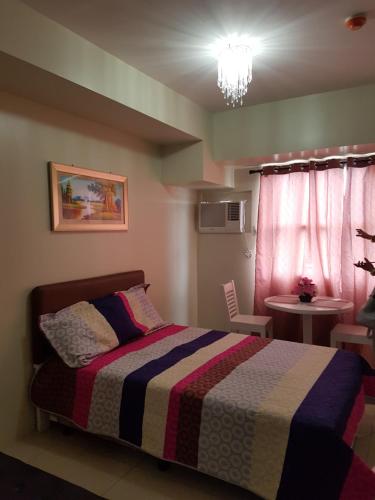 a bedroom with a bed with a colorful blanket at KC Studio 2 at Horizon 101 Cebu in Cebu City