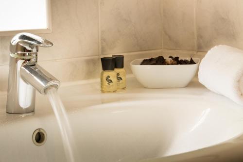 a bathroom sink with a faucet and a bowl of soap at Guy's Thatched Hamlet in Barton