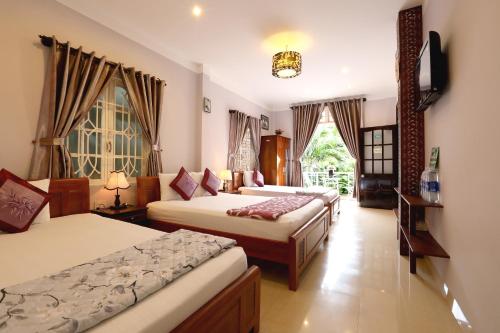 ホイアンにあるGreen Garden Homestayのベッドが2つと窓が2つある寝室