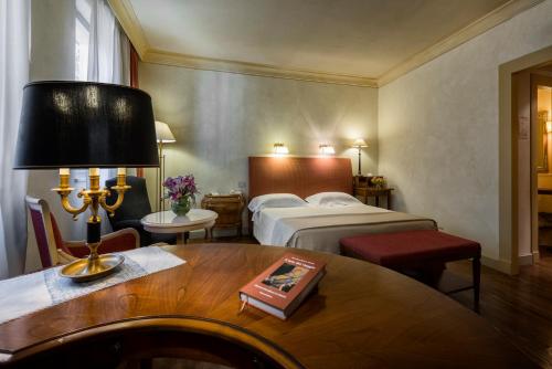 a hotel room with a bed and a table at Posta Donini 1579 - UNA Esperienze in San Martino in Campo