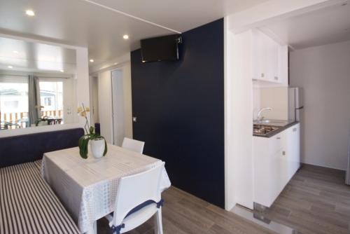 a dining room with a table and a kitchen at Camping Village Le Calanchiole in Capoliveri