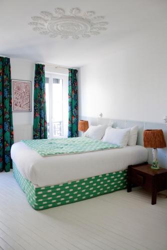 une chambre avec un grand lit avec des rideaux verts dans l'établissement Hôtel du Temps Paris, à Paris