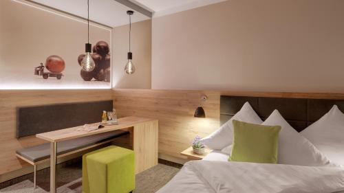 a bedroom with a bed and a table and a desk at Pfalzhotel Asselheim in Asselheim