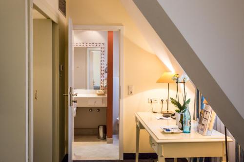 a bathroom with a sink and a desk with a mirror at Best Western Premier Hotel Rebstock in Würzburg