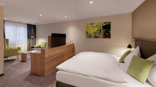 a hotel room with a bed and a desk and a television at Pfalzhotel Asselheim in Asselheim