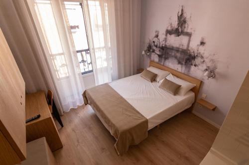 a small bedroom with a bed and two windows at Plaza Mayor Suites & Apartments in Madrid
