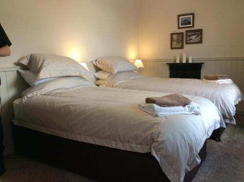 two beds in a room with white sheets and pillows at Crown and Anchor in Dundrennan