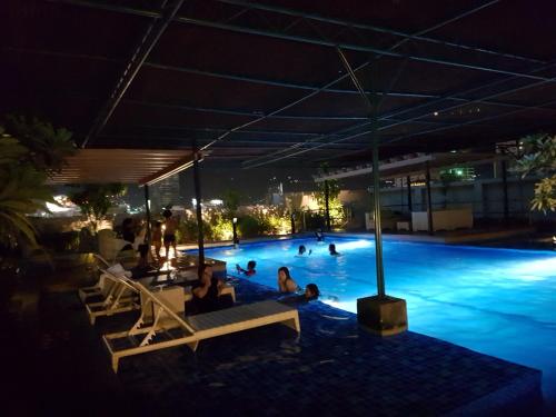 eine Gruppe von Personen in einem Schwimmbad in der Nacht in der Unterkunft Hermione's Haven at Horizon 101 Cebu in Cebu City