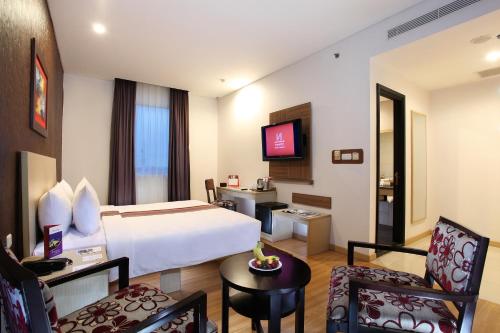 a hotel room with a bed and a table and chairs at Swiss-Belinn Panakkukang in Makassar