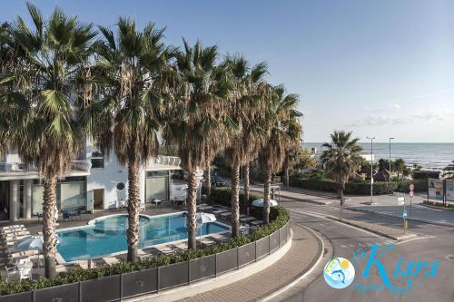 a resort with a pool and palm trees and the ocean at Kiara Residence in Giulianova