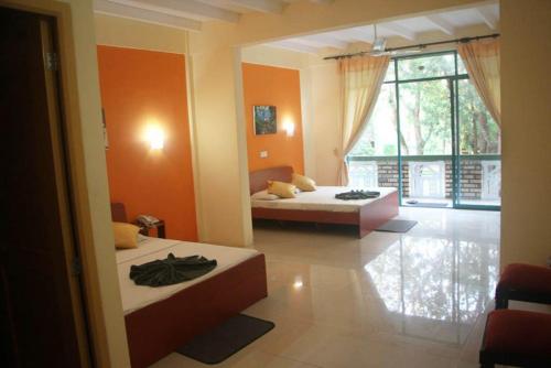 a bedroom with two beds and a large window at Hotel Eden Garden in Sigiriya