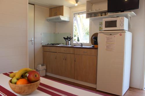 a kitchen with a bowl of fruit and a microwave at Camping Playa Arenillas in Islares