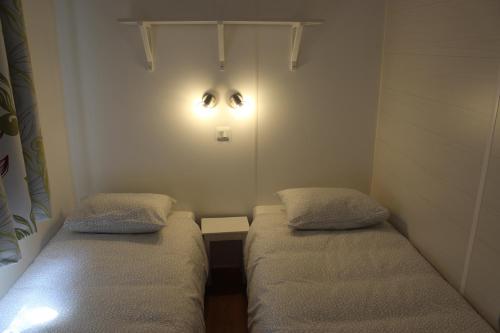 Camping Playa Arenillas في إسلاريس: سريرين في غرفة صغيرة مع أضواء على الحائط