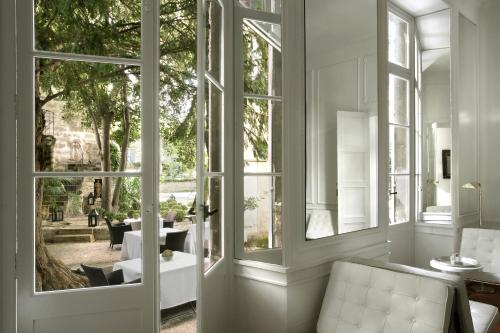 a room with large windows and a table with chairs at L'Hôtel Particulier in Arles