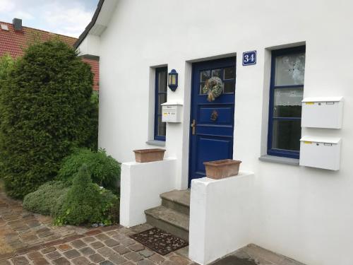 グロヴェにあるFerienwohnung Fritziの階段付きの白い家の青い扉